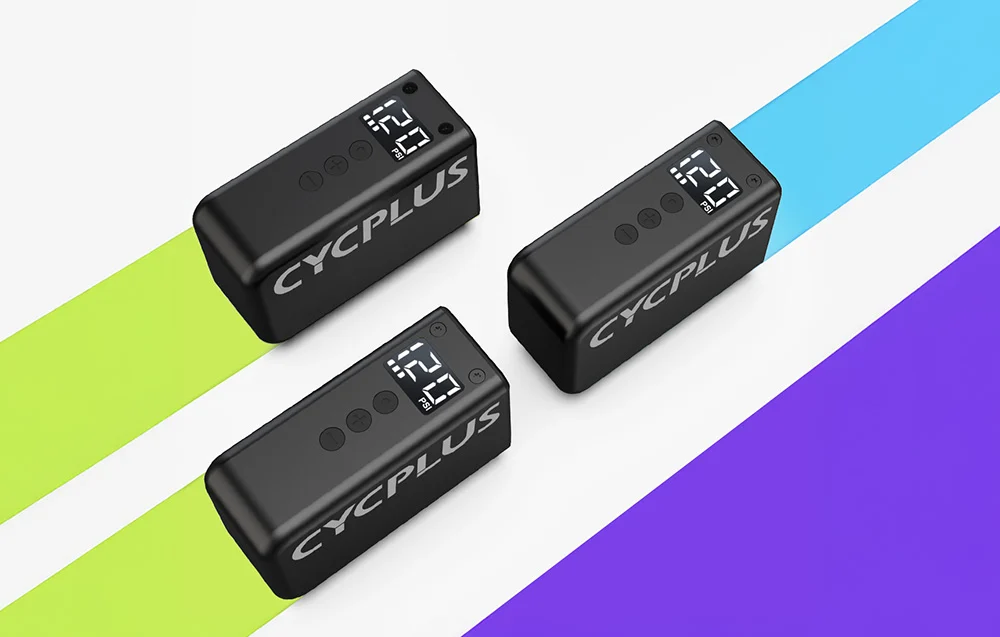 Trzy czarne pompki elektryczne Cycplus AS2 PRO z jasnymi wyświetlaczami ułożone na kolorowym tle.